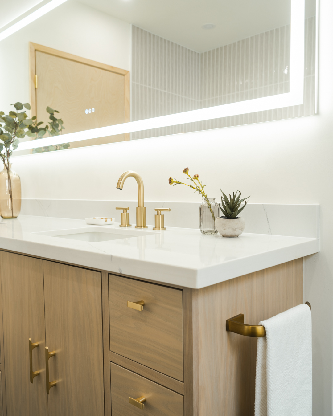 Randall Avenue bathroom vanity with brass fixtures and backlit mirror